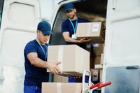 young-courier-and-his-colleague-unloading-cardboard-boxes-from-delivery-van